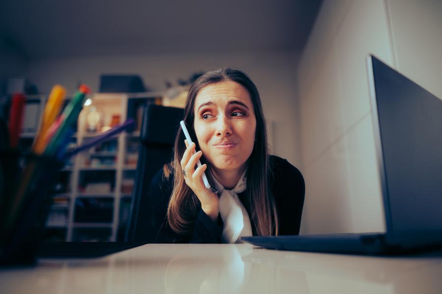A coordinator on the phone at her desk, one hand in her hair